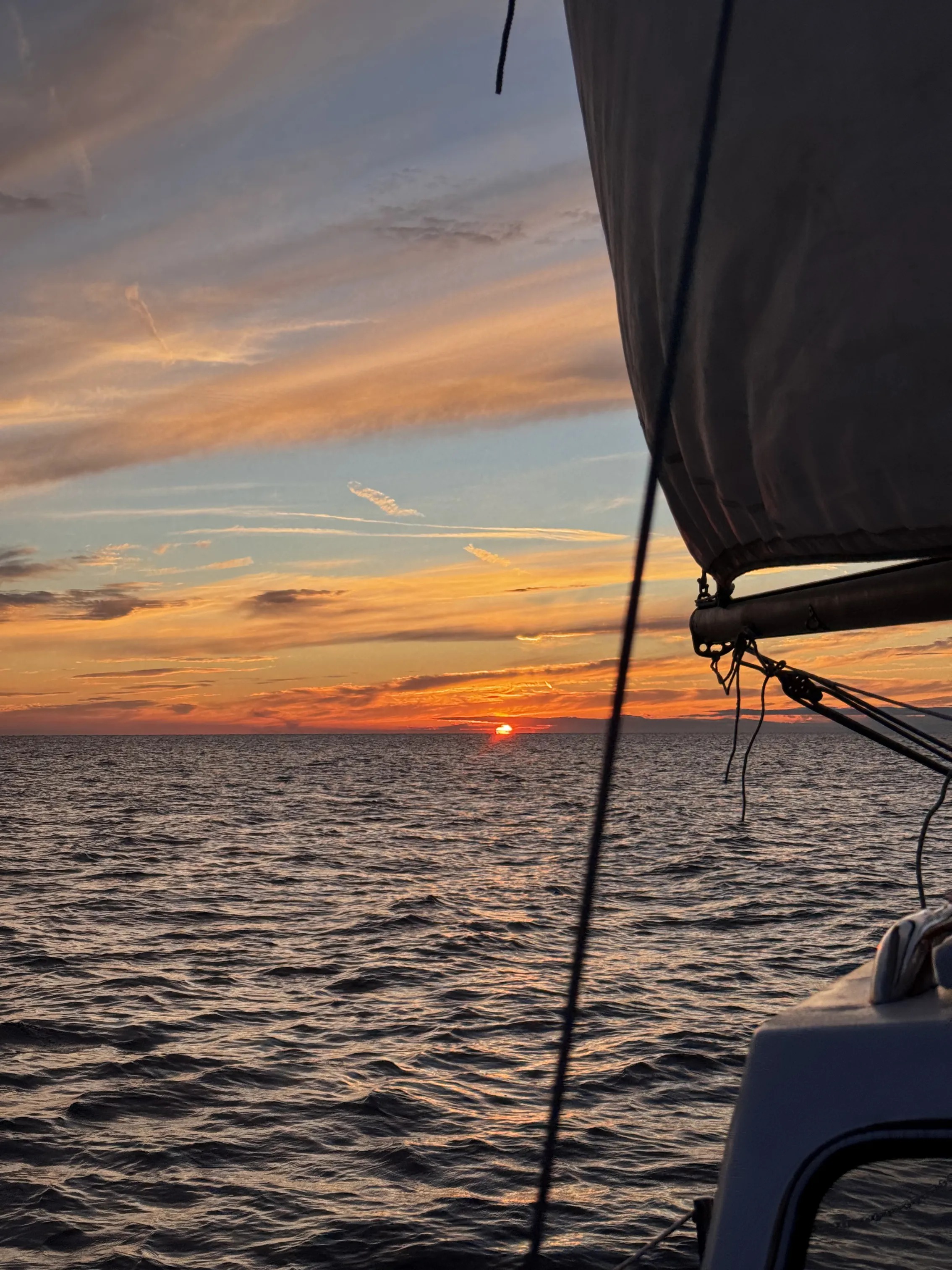 The sun setting on the horizon, seen past STRIGA's sail