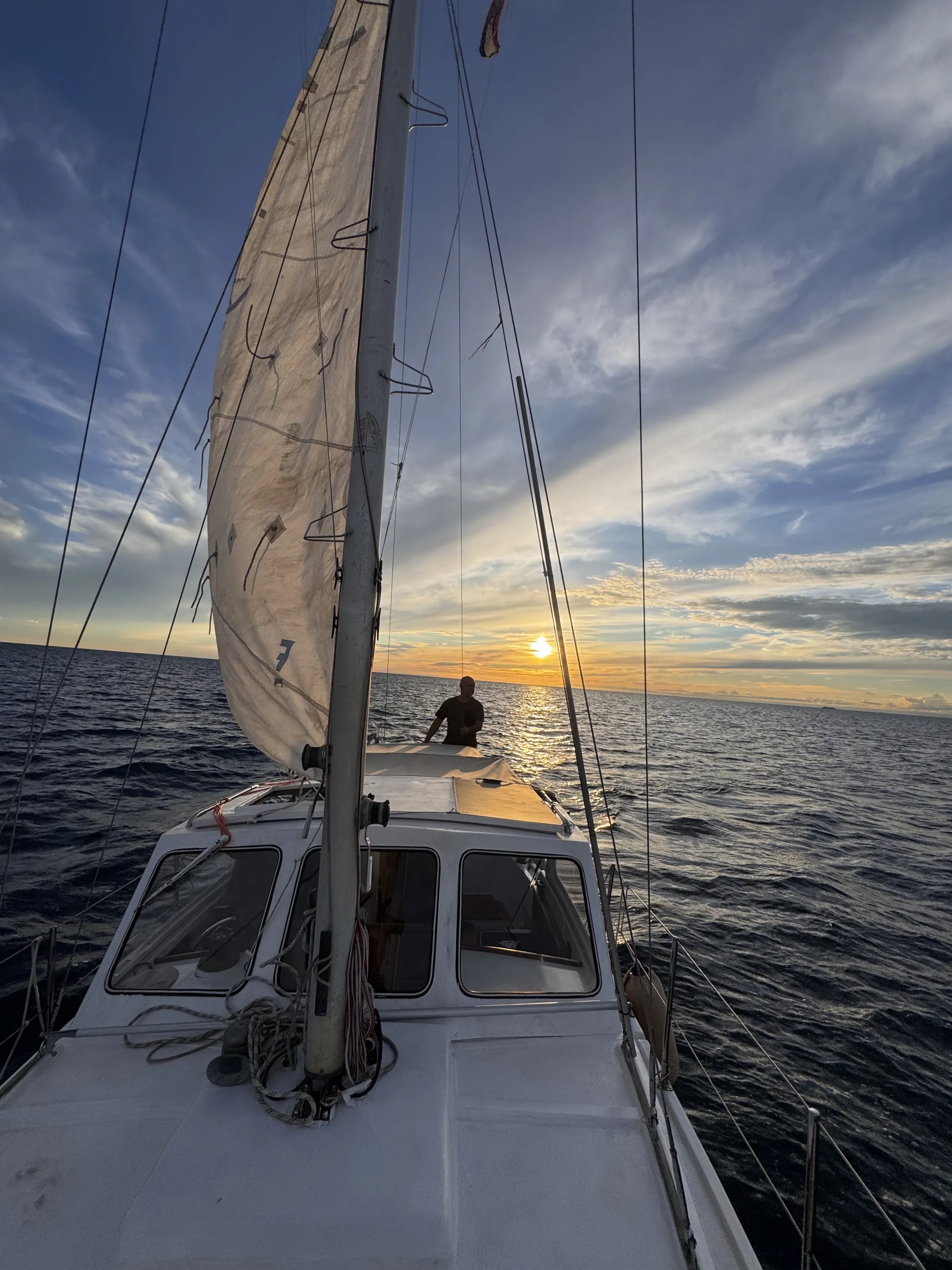 STRIGA under sail at sunset, Franz at the helm silhouetted against the golden sky